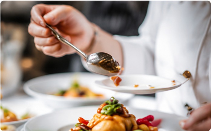 Chef finishing a plated dish with a spoon